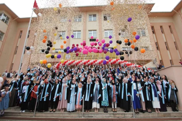 Okul binası önünde turkuaz bantlı kiralık kep-cübbelerle ortaokul 8. sınıf mezuniyet töreni
