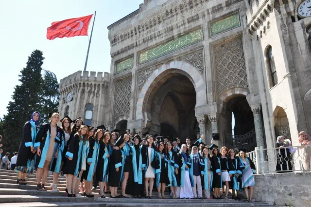 İstanbul Üniversitesi ana kapısı önünde kiralık alpaka cübbelerle üniversite mezuniyet fotoğrafı